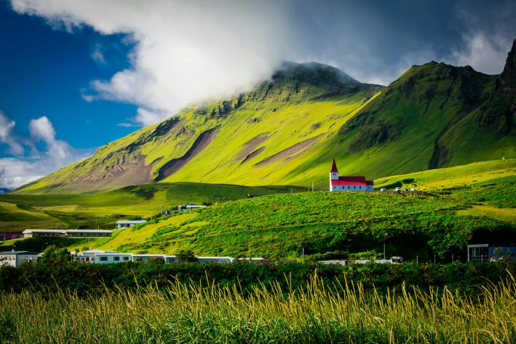 church and a village nestled within a green, mountainous landscape in iceland